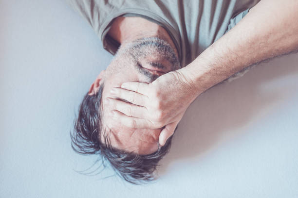Depressed lonely man crying in bed, top view