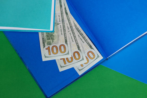 Financial concept. Three hundred dollar bills on an open book. bright green and blue background