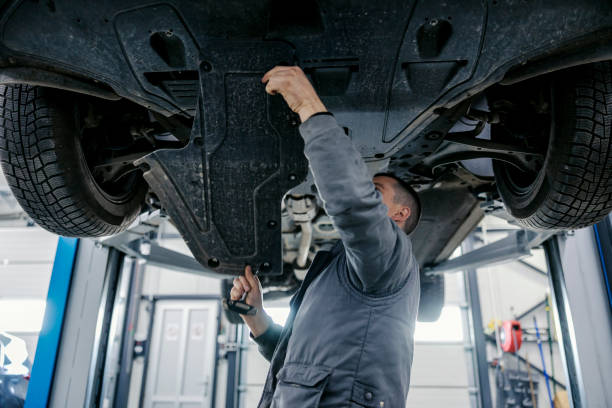 istock A car workshop worker is repairing car while standing under it at mechanic's shop. 2075453687