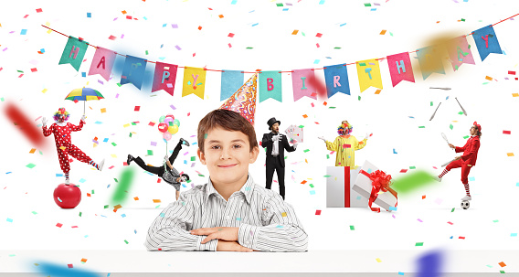 Birthday boy with a party hat celebrating with clowns and entertainers isolated on white background
