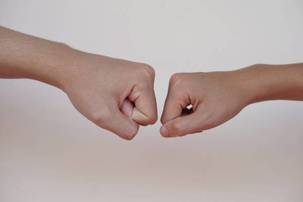 Close up  two hands bump their fists together for greeting. Concept, Body language. Hands gesture symbol for greeting, giving respect or approval as companionship between two people.