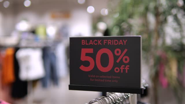Sign Black Friday sale 50 percent off promotion in huge clothing store Wide shot: signboard stand with sale 50 percent off in clothing store with blurry background Hurry up to get sale 50 percent off