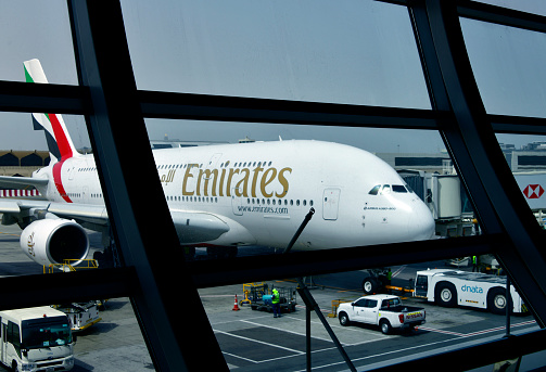 Al Garhoud district, Dubai: Emirates A380-842 (A6-EUM, MSN 225) at a passenger boarding bridge, seen from the terminal, with curved window frames - Dubai International Airport, terminal 3.