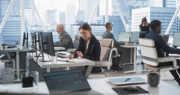 istock In Big Corporate Skyscraper Office: Beautiful Caucasian Female Business Manager Using Computer, Businesspeople and Experts Working Around Her, Analysing Statistics, Commerce Data, and Marketing Plans. 2075454676