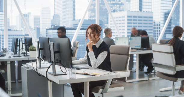 istock Young Female Data Scientist Typing On Desktop Computer In Bright And Diverse Corporate Office With Megapolis Window View. Professional Caucasian Woman Working In Tech Startup Company With Colleagues. 2075471900