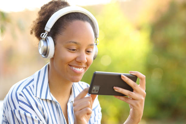 istock Black woman in a garden watching videos 2075483382