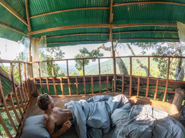 istock One man enjoying nature from his bed in a tree house 2075554194