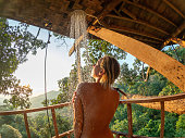Young woman under an outdoor shower in the rainforest at sunset