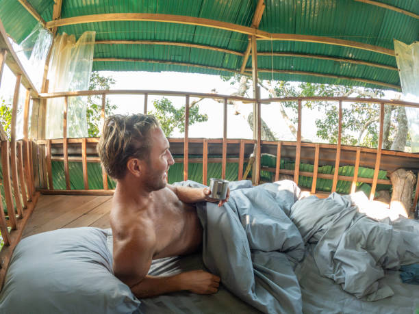istock One man enjoying nature from his bed in a tree house 2075555846