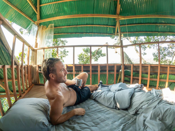 istock One man enjoying nature from his bed in a tree house 2075556941
