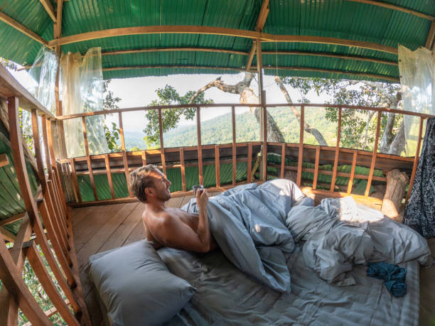 istock One man enjoying nature from his bed in a tree house 2075557497