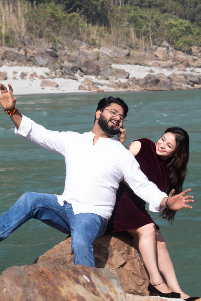 istock Love and laughter intertwine by the Ganges in Rishikesh as she playfully pulls at his cheek on a riverside rock 2075571693