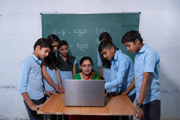 indian female teacher using laptop in her classroom to make children easier to understand, learn. Group of school kids in uniform looking at laptop screen. Education concept. maestra india que usa una computadora portátil en su salón de clases para que los niños sean más fáciles de entender y aprender. grupo de niños de la escuela en uniforme mirando la pantalla de la computadora portátil. concepto de educación.
