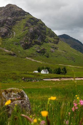 Lovely cottage by the River Coe that winds along valley in Scottish mountains. Beautiful and unspoilt nature surrounds charming white cottage that stands at the foot of a magnificent mountain peak.