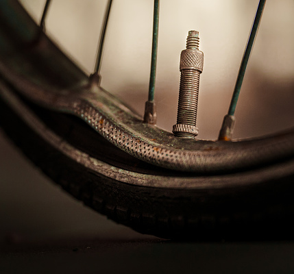 A close-up of an antique bicycle tire with a visible bolt and several bolts in the background.