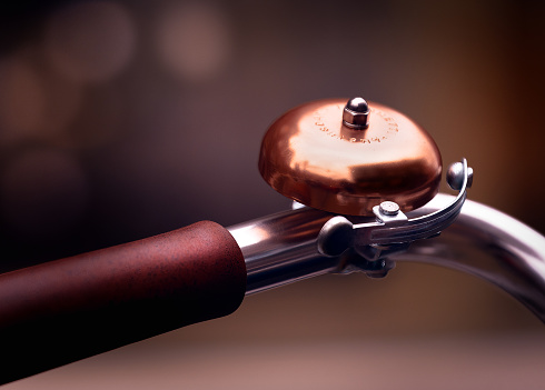 A close-up of a bicycle bell with a soft focus background.