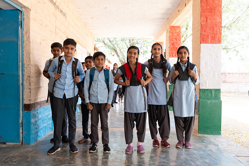 Happy group of indian rural children in school uniform standing looking at camera in school corridor. Education concept