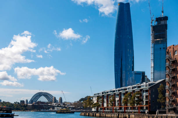Sydney, Australia - Aug 28, 2022: Crown Towers skyscraper and Sydney Harbour Bridge (left) as viewed from Jones Bay Wharf. Another skyscraper under construction.