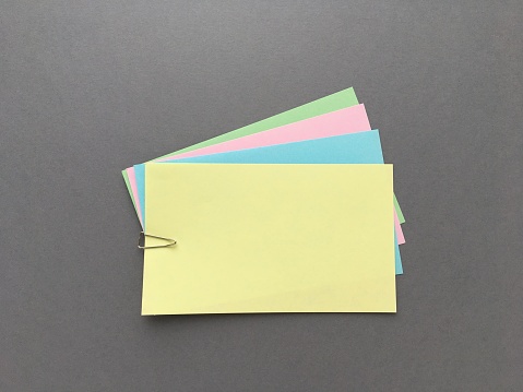 Colored sheets of notes fastened with a metal clip lie on a gray background