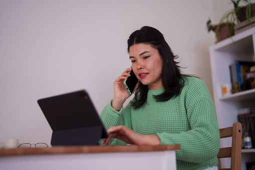 Millennial Asian woman using digital tablet, working at home office