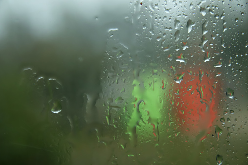 Rain drops on window glasses surface with cloudy background. Natural Pattern of raindrops on cloudy background. Blurred copy space. Sad mood. Out of focus.