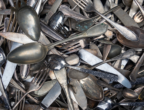 A large pile of old and antique cutlery for sale at the flea market
