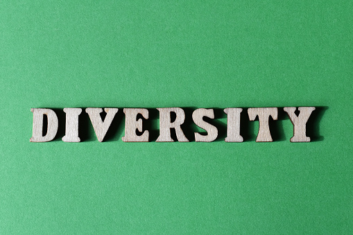 Diversity, word in wooden alphabet letters isolated on green background as banner headline