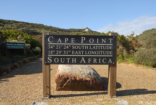Cape Point, Cape Town, South Africa. Cape Point sign showing longitude and latitude with Old Cape Point Lighthouse behind