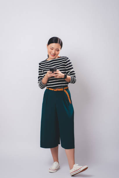 istock Asian woman enjoying using smartphone, isolated over white background. 2075670719