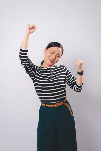 Photo of Asian woman happy confident make a winning gesture standing isolated on white background.