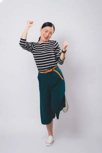 Photo of Asian woman happy confident make a winning gesture standing isolated on white background.