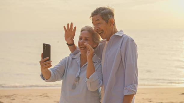 istock Senior couple using a smartphone to video call on the beach at sunset. 2075691421