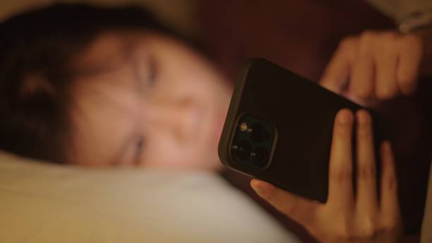 girl using smartphone on bed at night. - teenager problems typing teenagers only ストックフォトと画像
