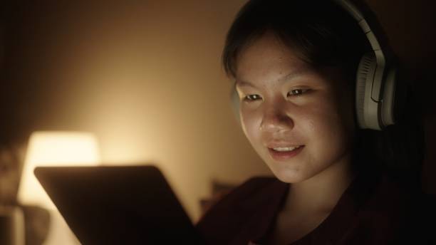 Teenager enjoy entertainment with digital tablet. Asian teenage girl enjoy entertainment with digital tablet in bed at night. divergent movie review stock pictures, royalty-free photos & images