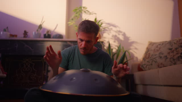 Man sitting on ground and playing handpan