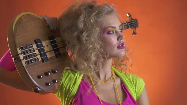 Retro 80s woman in colorful clothes with the guitar on her shoulder