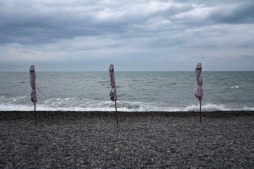 A deserted beach with umbrellas on the Sochi coast against the background of the Black Sea, Adler, Krasnodar Territory, Russia