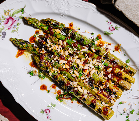 Baked asparagus with pine nuts on plate