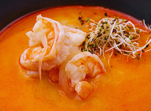 Traditional Thai soup Tom Yam in black bowl