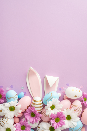 Perspectiva vertical de Vogue Easter capturada desde la vista superior, con huevos, orejas de liebre, margaritas y confeti sobre una base de color púrpura suave, proporcionando un área para sus mensajes o marketing photo