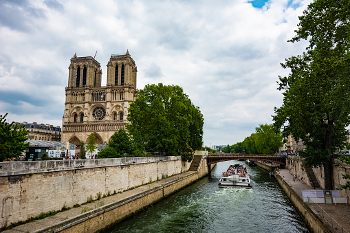 Notre-Dame  with canal next to it and tourist boat.