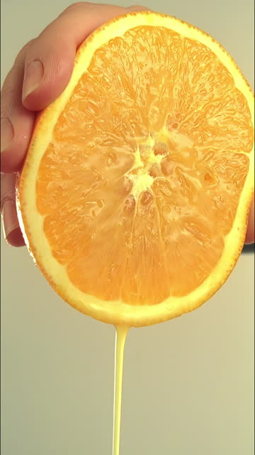 Hand squeezing a juicy orange half