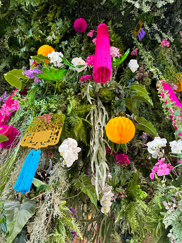 Stock photo showing close-up, low angle view of decoration of artificial foliage and flowers with paper Chinese lantern decorations and tassels.