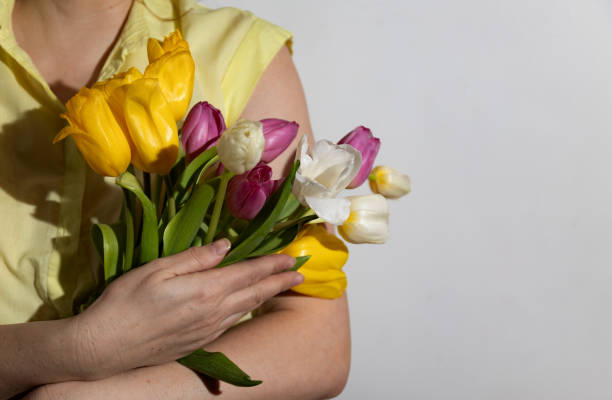 istock Multi-colored tulips in the hands of a woman in a room illuminated by sunlight 2075780077