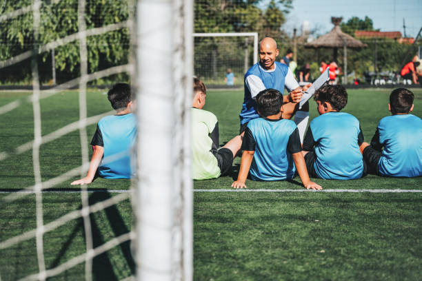 istock coach sitting with boy soccer team on pitch and drawing on match board 2075823698