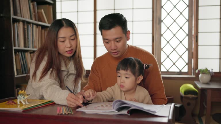 Happy, family and girl with homework, education and Japan with activity, writing and studying. Parents, mother and father with a kid, book or child development with fun, learning and bonding together