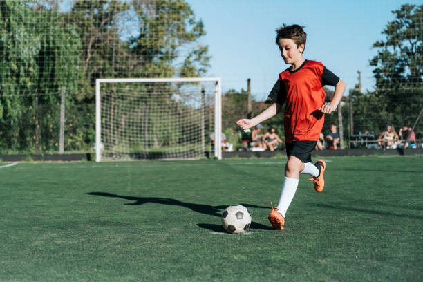 soccer boy kicking the ball on field