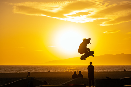 Los Angeles, United States - April 20th, 2023: A skater in Venice Beach performs a jump in front of the setting sun