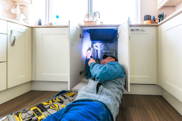 istock Plumber looking at pipes under kitchen sink 2075834888