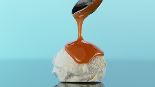 Table top view of Scoop of vanilla ice cream covered with caramel on blue background